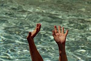 hands of black Migrant detail on boat asking for help from the sea background photo