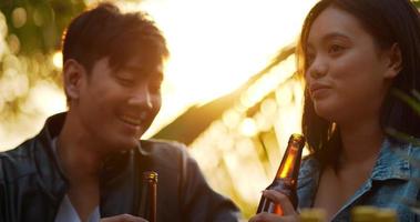 imágenes de amigos asiáticos felices cenando juntos - jóvenes sentados en la mesa del bar brindando una cena con botellas de cerveza al aire libre - gente, comida, estilo de vida de bebida, concepto de celebración de año nuevo.
