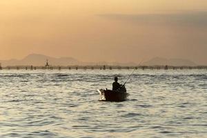 silueta de pescador al atardecer en el puerto de Chioggia de la laguna de Venecia desde un barco