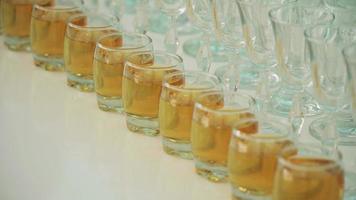 Gläser mit Alkohol in einer Reihe auf einem weißen Tisch video