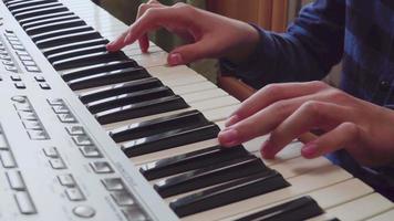 närbild av fingrar av en pojke inlärning spelar de piano. video