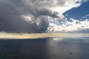 barco navegando hacia la tempestad del mar y la vista aérea del cielo despejado foto
