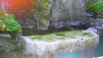 cascada y musgo verde en la roca con agua pulverizada y luz video