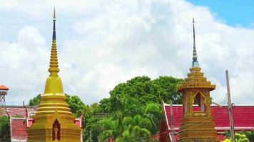 Spitze von zwei goldenen Pagoden im buddhistischen Tempel und graue Wolke im Zeitraffer video