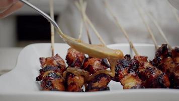 verser la sauce aux cacahuètes sur le satay de poulet video