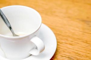 Closeup and crop white coffee cup and spoon with saucer on wooden table. photo