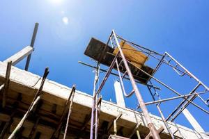 mire hacia arriba la vista del andamio del sitio de construcción en el sitio de construcción del hogar con bengalas solares y fondo de cielo azul. foto