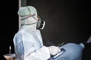 Professional technical man in prevention suit with his sterilizing machine and disinfecting water sprays in the outdoor field for purifying coronavirus photo