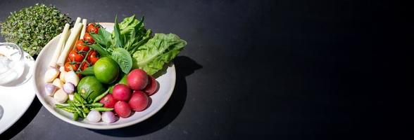 los ingredientes de la ensalada picante se preparan en una mesa de granito negro con varias verduras y hierbas. camino de recortes foto