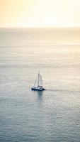 un yate de velero mínimo está navegando en el mar en calma, tome esta imagen desde arriba de la montaña desde el cabo de phuket, phuket, tailandia, con teleobjetivo. foto