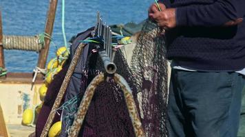 le vieux pêcheur répare les filets de pêche avec ses mains video