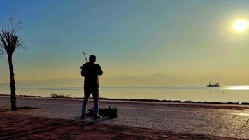 Street Musician Playing Violin by the Beach at Foggy Sunset
