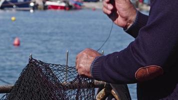 le vieux pêcheur répare les filets de pêche avec ses mains video