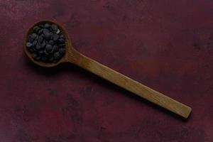 Melt chocolate buttons on wooden spoon on burgundy rustic background photo