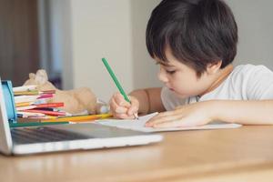 Education concept,School kid using grey colour pen drawing or sketching on paper,Portrait  boy siting on table doing homework in living room,Child enjoy art and craft activity at home on weekend photo