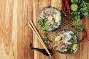 Pho Bo, Vietnamese Fresh Rice Noodle Soup with Beef, Herbs, and Chili. photo