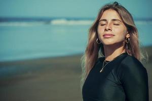 Close up of beautiful young blonde girl with her eyes closed on the beach. photo