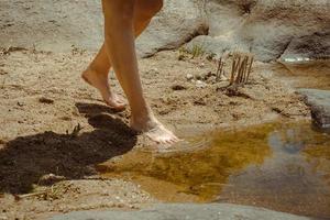 pies de mujer relajándose sintiendo la arena y el agua del río. foto