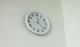 jakarta, indonesia - 27 de enero de 2023 - reloj colgante de pared simple de cuarzo blanco clásico imagen aislada en una pared blanca vacía foto