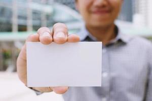 business man in hand hold show blank white card mock up with rounded corners. Plain call-card mock up template holding arm. Plastic credit name card display front. Business branding concept. photo