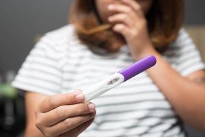 Young woman looking show in hand at checking pregnancy test kit. She's is checking her pregnancy exam. success congratulation new mom. photo