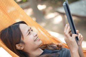 Asian woman looking at earnings on a computer. In an orange spread in a coffee shop where she can go to work. amidst green nature photo