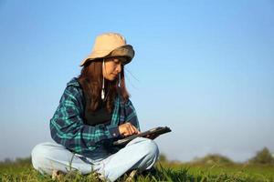 Asian female farmer uses computer to analyze rice growth. photo