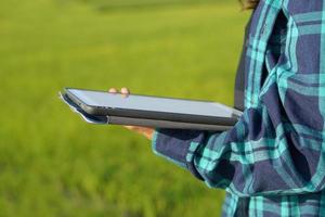 Asian female farmers use computers to analyze the growth of rice plants. photo