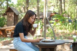 las mujeres asiáticas están felices de sentarse y trabajar en una cafetería. hay árboles verdes rodeados de naturaleza. la planificación empresarial es una buena idea. foto