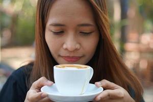 Asian woman inhaling aromatic coffee photo