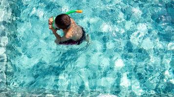 niño divirtiéndose jugando en la piscina foto