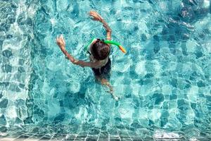 niño divirtiéndose jugando en la piscina foto