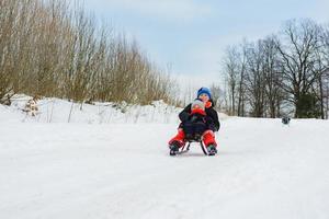 boy and girl are riding on sleds photo