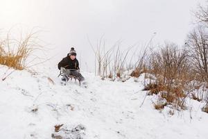 the boy is hiding from the hills in the sled in the park photo