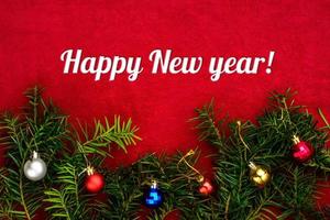 Inscription Happy New Year on red background with Christmas tree and balls with top view photo