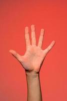The human hand shows five fingers, which symbolizes affection. Isolated on a red background photo