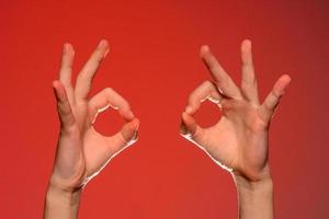 dos manos humanas muestran un signo correcto, aisladas en un fondo rojo foto