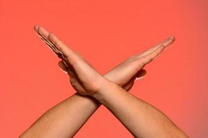 Human hands folded crosswise, which symbolize the wings of a bird or the sign of xx, isolated on a red background photo