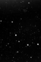 a bokeh of white snow on a black background photo