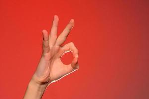 The human hand shows the sign ok symbolizing the positive, isolated on a red background.