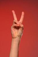 The soft hand showing the victory sign is isolated on a red background photo