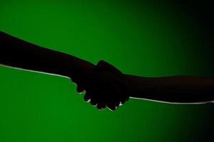 apretón de manos de dos manos, aislado en un fondo verde, que simboliza la amistad y la reconciliación