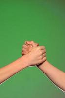 Two hands handshake, isolated on a green background, symbolizing friendship and reconciliation photo