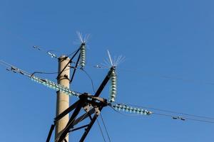 Concrete electricity pylon with glass insulators and bird spikes. Electric power concept. Bird protection for power lines. photo