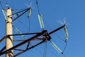 Concrete electricity pylon with glass insulators and bird spikes. Electric power concept. Bird protection for power lines. photo