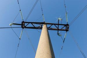 Concrete electricity pylon with glass insulators and bird spikes. Electric power concept. Bird protection for power lines. Bottom view photo