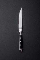 Metal kitchen knife on a dark textured concrete background photo