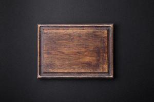 tabla de cortar de madera vacía sobre fondo de hormigón con textura oscura foto