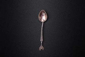 Empty metal spoon on dark textured concrete background photo