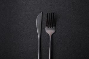 Metal kitchen knife and fork on a dark textured concrete background photo